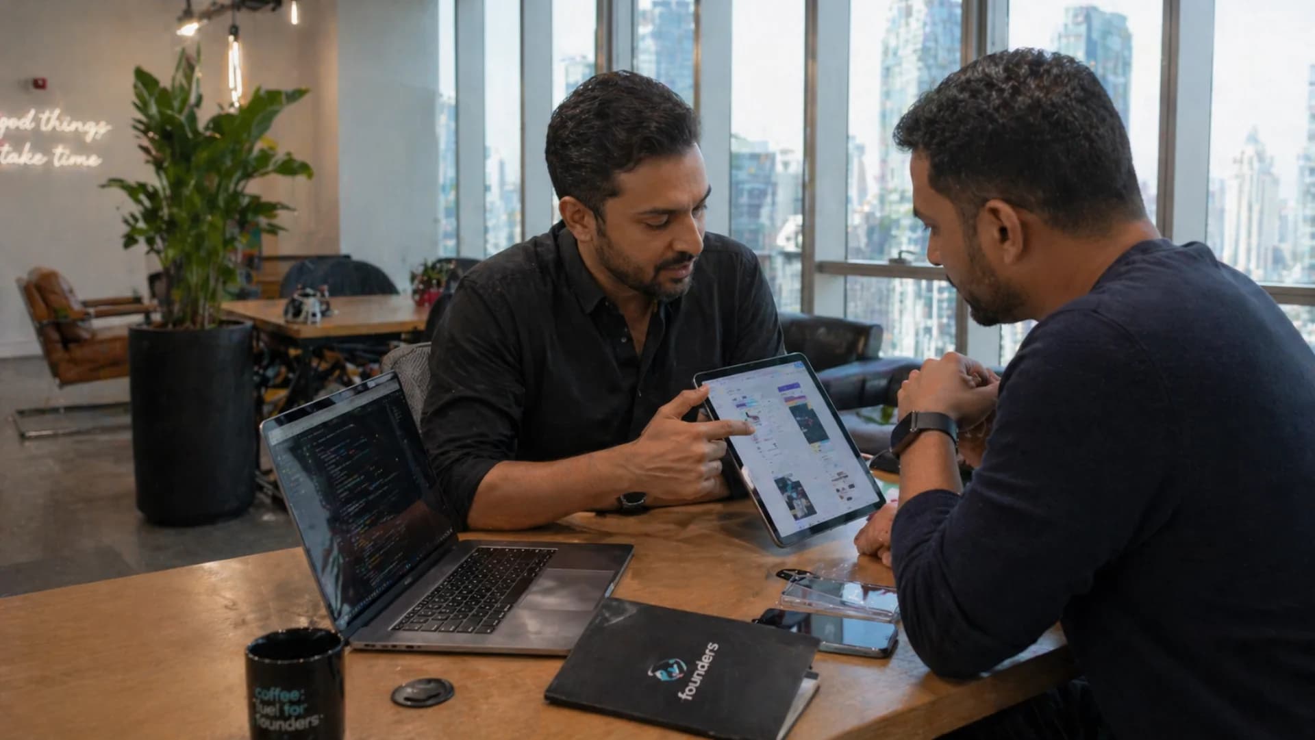 Mobile app development cost Dubai 2026 — UAE startup founder reviewing mobile app prototype on iPad with developer in Dubai co-working space