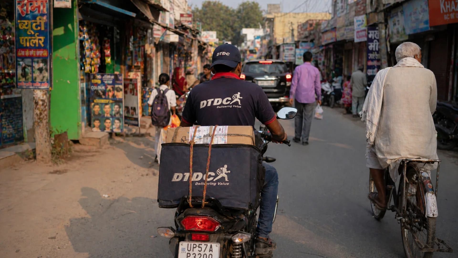 DTDC integration for Tier-2/3 India shipping — DTDC delivery partner navigating narrow Indian street with parcels on motorcycle